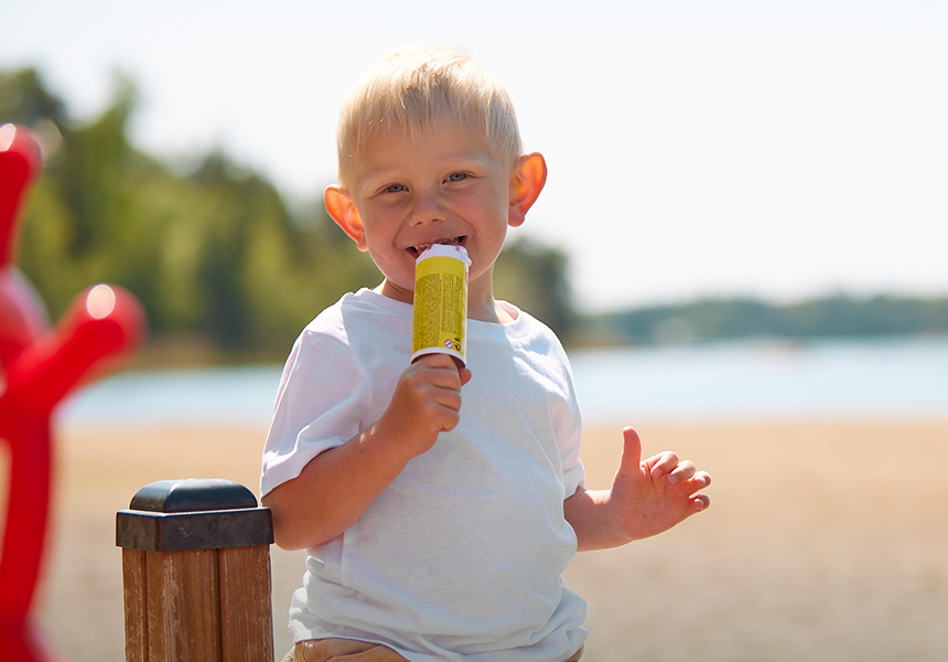 Pojke äter glass vid stranden.