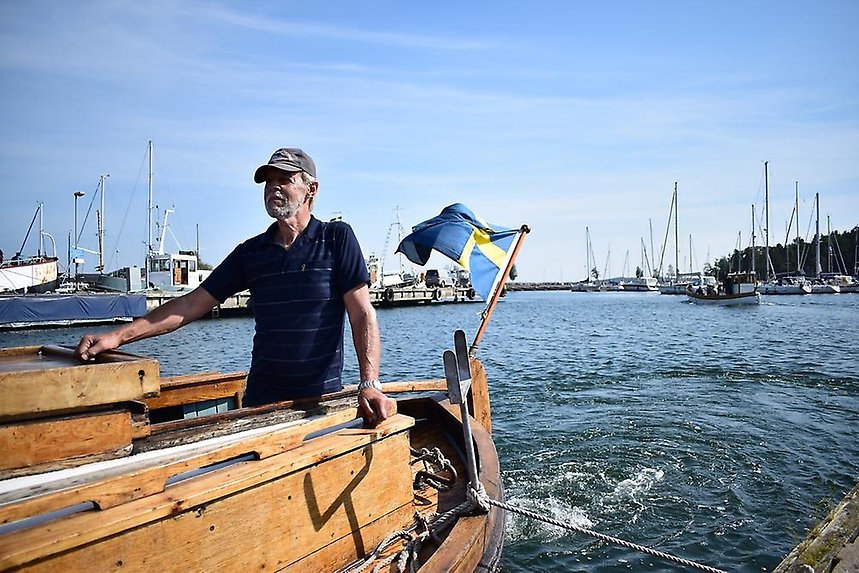 En man står i en båt gjord av trä.